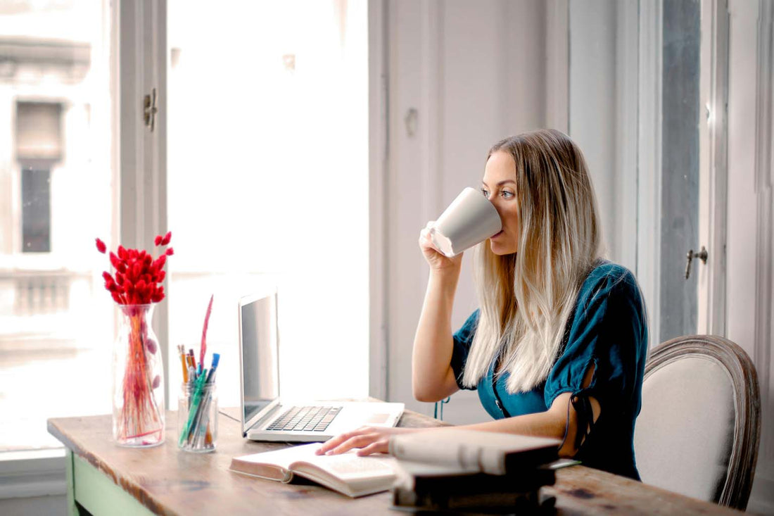 Young adult works at desk with coffee