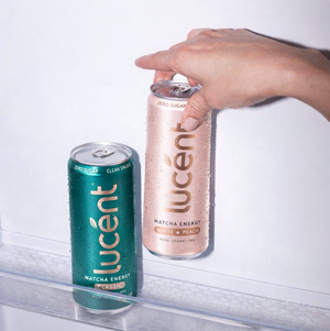 Two cans of lucent energy drink being taken out of a refrigerator.