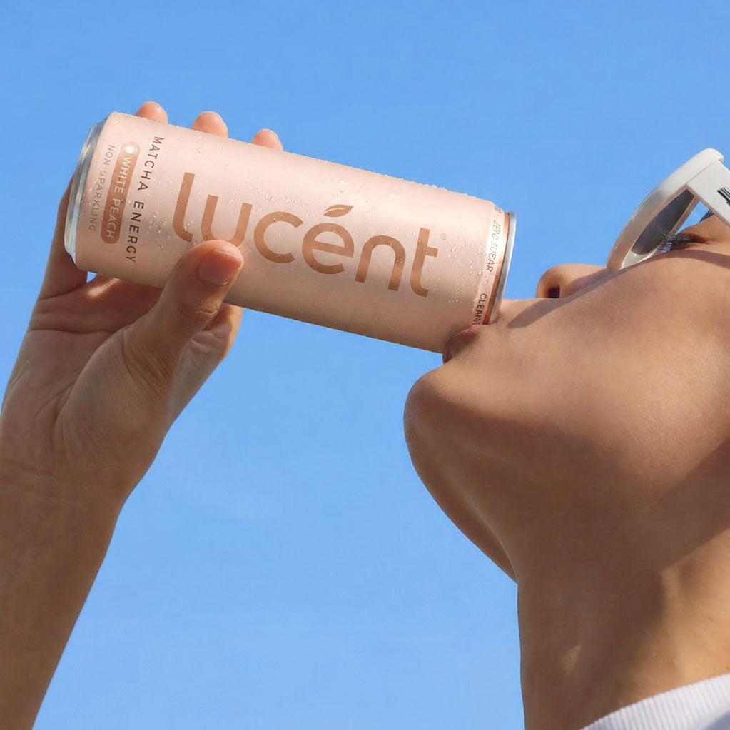 Person holding a can of Lucent against a clear blue sky
