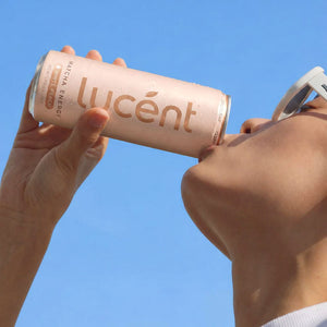 Person holding a can of Lucent against a clear blue sky