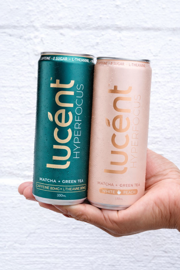 Two Lucent matcha energy drink cans held in a hand against a light background.