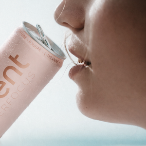 Person holding a white peach can close to their mouth on a light background.